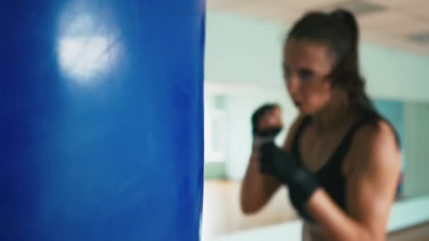 Красивая смешанная гонка Кикбоксинг женщина тренировки боксерская груша в фитнес-студии свирепый прочность подходит тело кикбоксер серии — стоковое видео