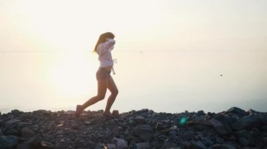 Gün batımında sahilde yavaş çalışan kadın