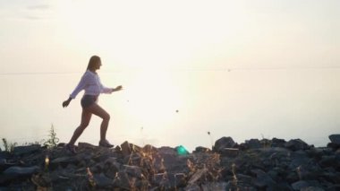 Gün batımında sahilde yavaş çalışan kadın