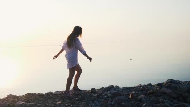 Vrouw met lopend op het strand in slow motion bij zonsondergang — Stockvideo