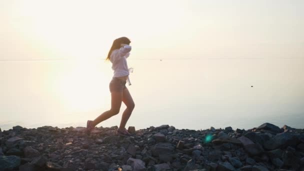 Vrouw met lopend op het strand in slow motion bij zonsondergang — Stockvideo