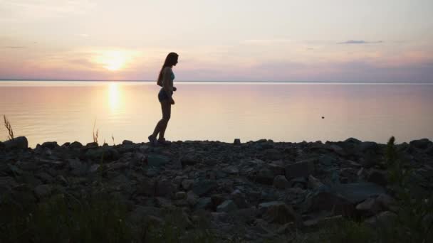 Kvinna med kör på stranden i slow motion vid solnedgången — Stockvideo