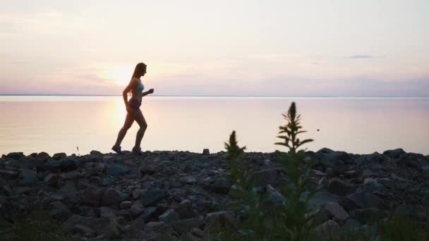 Femme avec course sur la plage au ralenti au coucher du soleil — Video