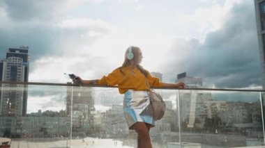 Kentsel şehir sokakları arka planda kulaklık ile müzik dinlemek Genç Sevimli çekici genç kız portresi. Sarı bluz ve gümüş etek giyen kadın