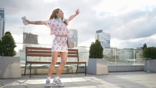 Gelukkig schattig millenial hipster meisje plezier buiten bij stad straten stedelijke achtergrond. Schoonheid vrouw spinnen, springen en lachen. Vrijheid. Slow motion — Stockvideo