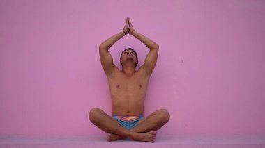 Çıplak gövde pratik yoga fitness karışık yarış İspanyol Genç adamla, pembe arka plan egzersiz. Spor, meditasyon ve yaşam tarzı kavramı. İyi bir sağlık için huzurlu meditasyon