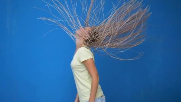 Chica hipster de moda sacudiendo sus trenzadas coletas de pelo y girando sobre fondo azul — Vídeos de Stock