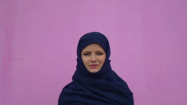 Emin gülümseyen sakin profesyonel iddialı pembe arka plan üzerinde seyir türban başörtüsü giyen güzel genç Müslüman iş kadın portresi kapatın — Stok video