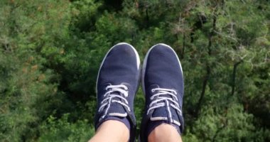 Havadan Pov görünümü. Uçan güzel orman ağaçları bitti. Hava kamera çekim ve çerçeve içinde mavi spor ayakkabıları ile insan bacaklar. Manzara panorama