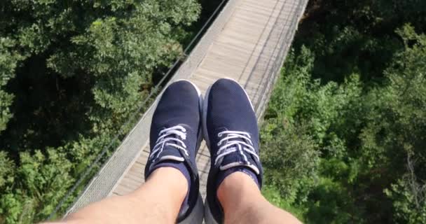 Vista aérea POV. Volando sobre los hermosos árboles del bosque. Cámara aérea de tiro y piernas humanas con zapatillas azules en el marco. Panorama del paisaje — Vídeos de Stock