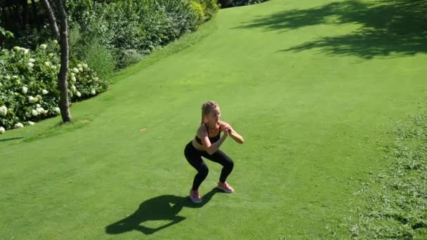 Jonge vrouw uit te oefenen, stretching en opleiding gehurkt buitenshuis. Gezond, fitness, wellness-levensstijl. Sport, cardio, workout concept — Stockvideo