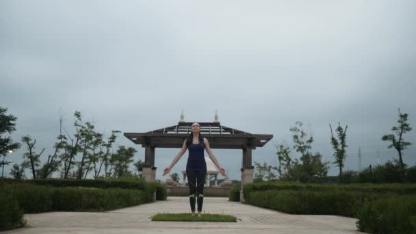 Young caucasian woman in sportswear relaxing by practicing yoga barefoot in the city park. Sunrise background. Slow motion — Stock Video