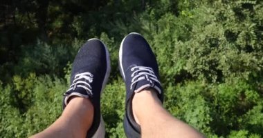 Havadan Pov görünümü. Uçan güzel orman ağaçları bitti. Hava kamera çekim ve çerçeve içinde mavi spor ayakkabıları ile insan bacaklar. Manzara panorama