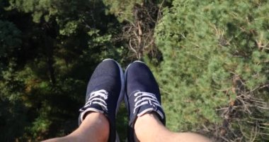 Havadan Pov görünümü. Uçan güzel orman ağaçları bitti. Hava kamera çekim ve çerçeve içinde mavi spor ayakkabıları ile insan bacaklar. Manzara panorama