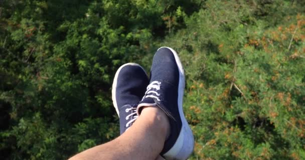 Vista aerea POV. Sorvolando i bellissimi alberi della foresta. Fotocamera aerea ripresa e gambe umane con scarpe da ginnastica blu in cornice. Panorama paesaggistico — Video Stock
