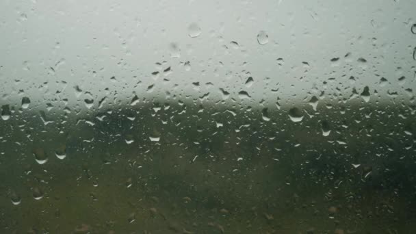 Капли дождя появляются на оконном стекле, начинается дождь, капает фон — стоковое видео