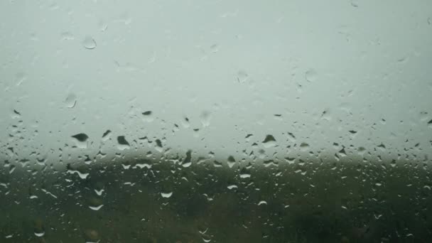 Капли дождя появляются на оконном стекле, начинается дождь, капает фон — стоковое видео