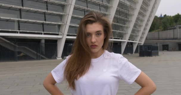 Retrato dramático de la hermosa mujer caucásica en camisa blanca que mira grave cámara lenta suave luz natural en la cara al aire libre en la ciudad. Escaleras en segundo plano — Vídeos de Stock