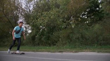 Karışık yarış hipster adam longboarder yarış yavaş çekimde bir şehir parkı