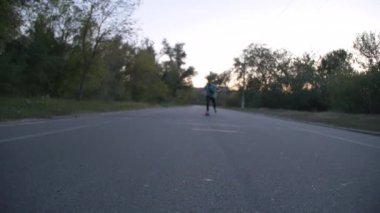 Karışık yarış hipster adam longboarder yarış yavaş çekimde bir şehir parkı