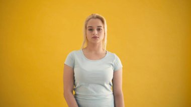 Çekici genç beyaz sarışın artı boyutu modeli kamera sarı arka plana bak