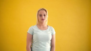 Genç sarışın beyaz artı boyutu model hayran sarı arka plan şaşırttı