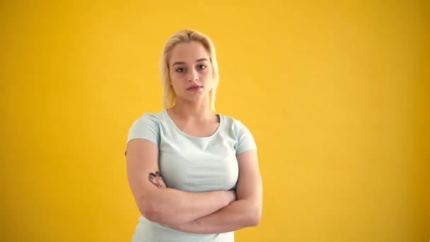 Jonge blonde Kaukasische plus grootte model poseren glimlachend met overschrijding van de handen op gele achtergrond — Stockvideo