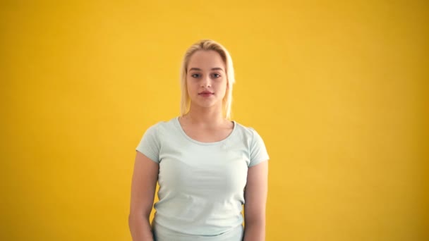 Happy blond modèle plus la taille montre geste de la main okey ou bon travail à fond jaune — Video