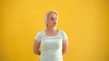 Üzgün ve düşünceli sarışın beyaz artı boyutu model sarı arka plan, kötü bir ruh hali içinde