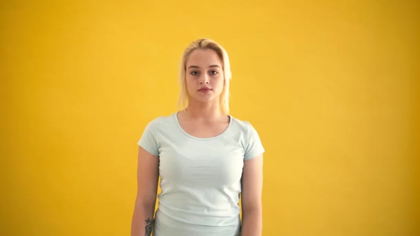 Смішна блондинка кавказька модель плюс розмір показує мирний жест на жовтому тлі — стокове відео