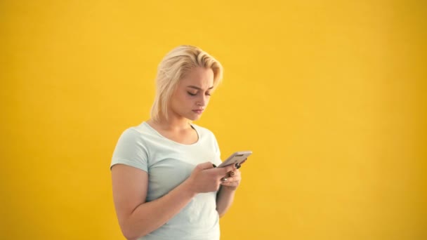 Smartphone cep telefonu ile sarı arka plan ağır çekim, sürpriz sarışın artı boyutu modeli manifatura — Stok video