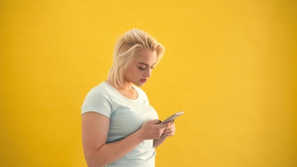 Unglückliches blondes Plus-Size-Model überrascht Kontrollnachricht am Telefon auf gelbem Hintergrund — Stockvideo