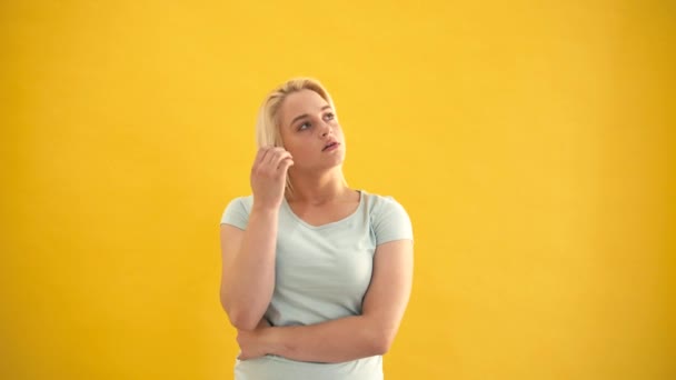 Sad blond caucasian plus size model in a bad mood at yellow background slow motion — Stock Video