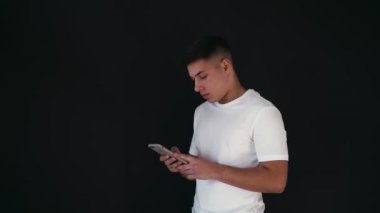 Şaşırdım ve mutlu genç adam anlamına gelir ve telefon elinde tutar. Merak ediyorum ve hayrete düşürdü. İçinde inanamıyorum. Siyah arka plan üzerine izole