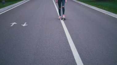 Pembe windstopper eğleniyor genç güzel güzel sarışın hipster kadında kaykay longboard yokuş aşağı yavaş güzel yolda sürme