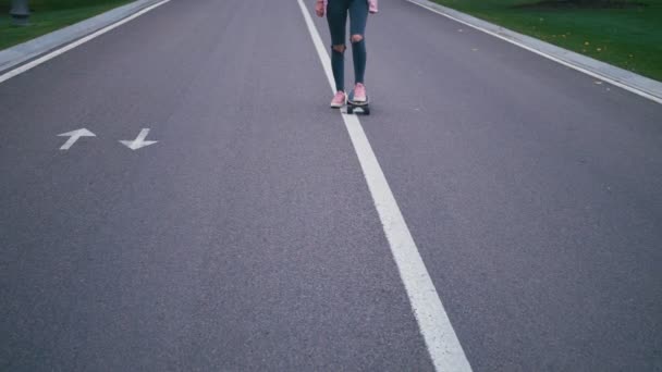 Mladá žena docela krásné blond bokové v růžové windstopper baví na koni skateboard longboard z kopce na krásné silnici v pomalém pohybu — Stock video