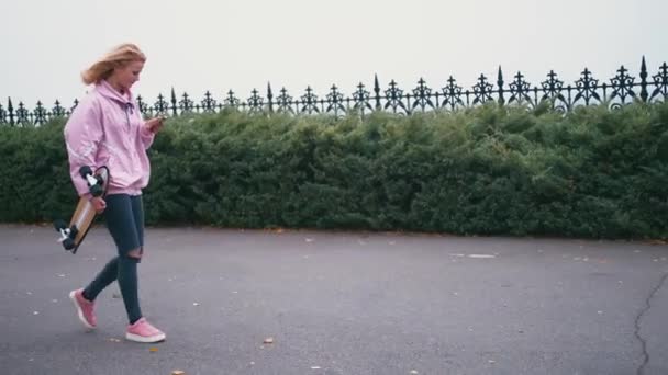 Mujer hipster rubia bonita con longboard de skate — Vídeos de Stock