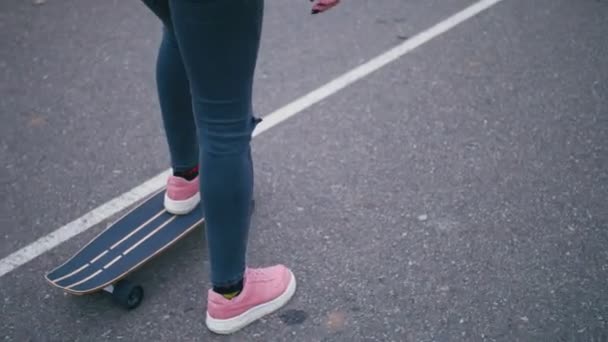 Ung ganska vacker blond hipster kvinna i rosa windstopper ha kul ridning skateboard longboard nedförsbacke på vackra road i slow motion — Stockvideo