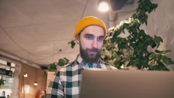 Hipster Homem Chapéu Amarelo Usando Computador Portátil Trabalhando Enquanto Sentado — Vídeo de Stock