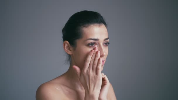 Schoonheid Model meisje portret. Mooie vrouw gezicht. Geïsoleerd op een grijze achtergrond. Mooi meisje haar gezicht aan te raken — Stockvideo