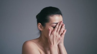 Güzellik modeli kız portre. Güzel bir kadın yüzü. Gri arka plan üzerinde izole. Güzel kız onun yüzüne dokunmak.
