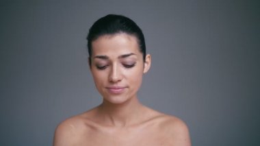 Sevimli güzel milennial genç esmer kadın gri arka plan üzerinde hava öpücük gönderme