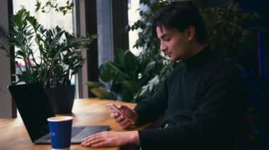 Karışık yarış adam akıllı telefon kullanarak ve kafede kahve içme dizüstü bilgisayar ile çalışma