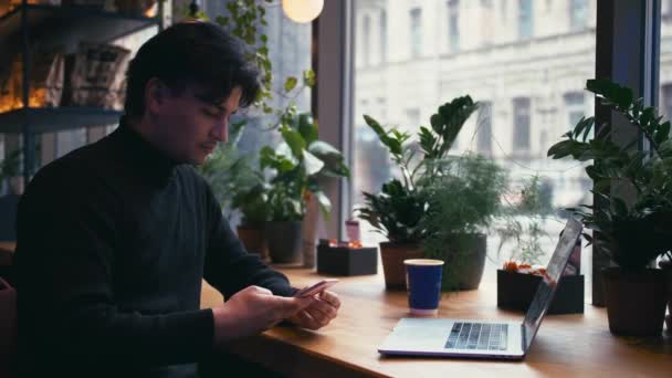 Blandad ras man arbetar med laptop och smart phone Café — Stockvideo