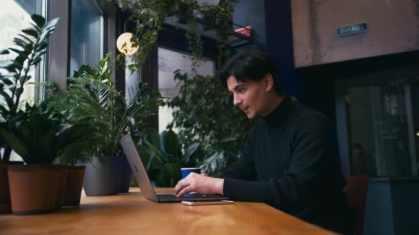 Смешанный гонщик работает с ноутбуком и смартфоном в кафе — стоковое видео