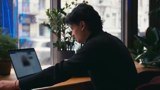 Homme de race mixte travaillant avec ordinateur portable et téléphone intelligent au café — Video