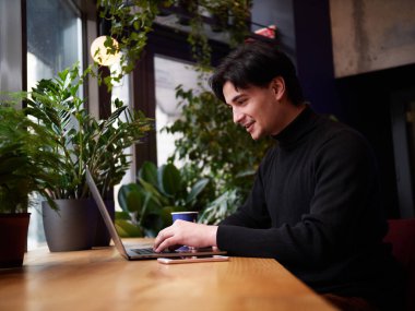 Karışık yarış adam dizüstü bilgisayar ve akıllı telefon café'de çalışma