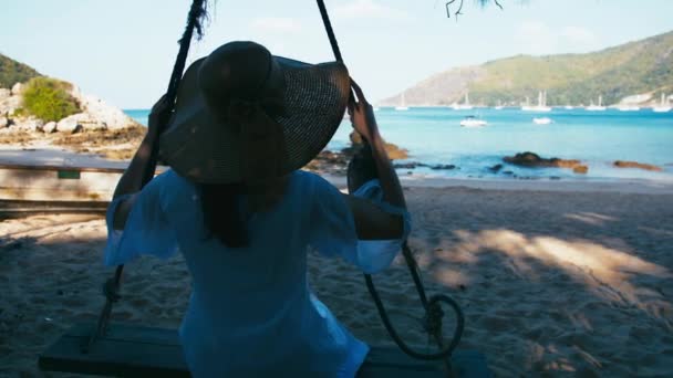 Zorgeloos gelukkige vrouw in hoed op schommel op prachtige paradijs strand in Thailand — Stockvideo