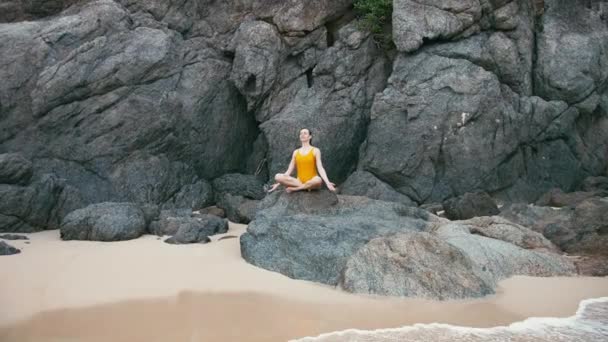 Mujer caucásica en traje amarillo practicando yoga ejercicio de fitness en la orilla del mar — Vídeos de Stock