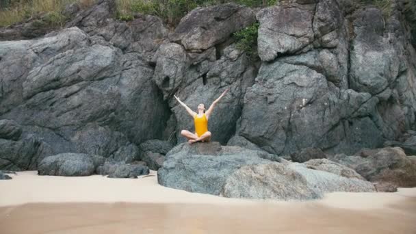 Caucasian woman in yellow smiwsuit practicing yoga fitness exercise at seashore — Stock Video